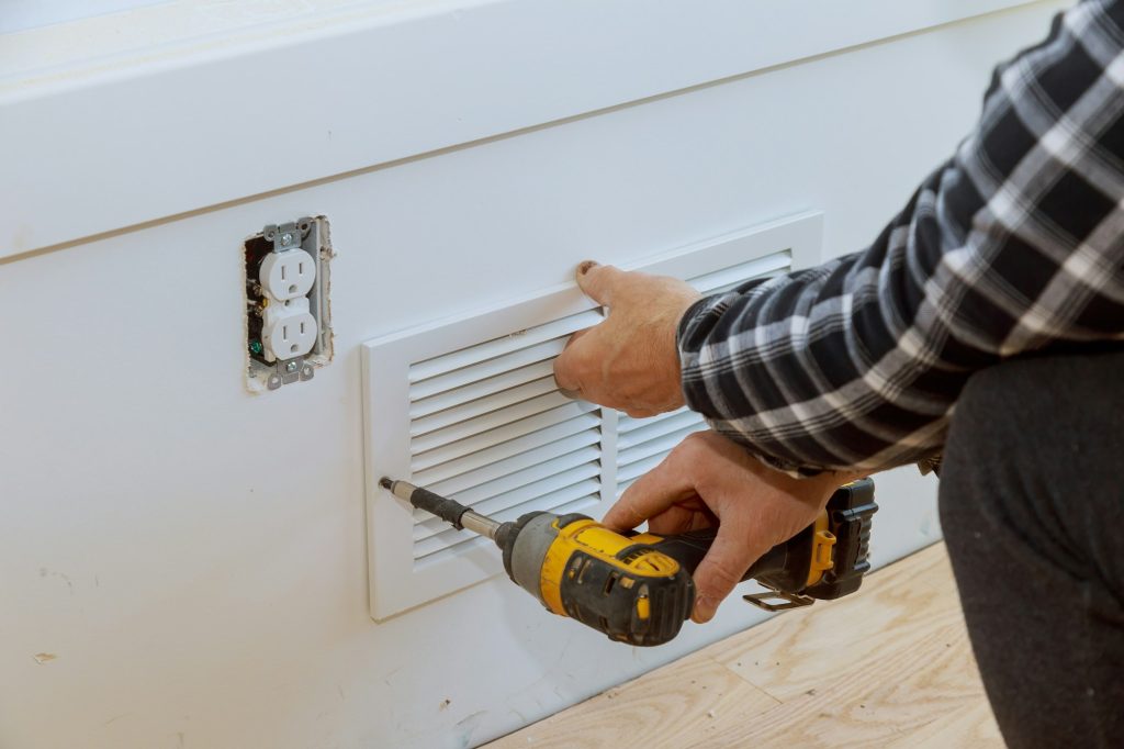 Man is installing the wall cover ventilation vent maintenance repair works renovation in the new